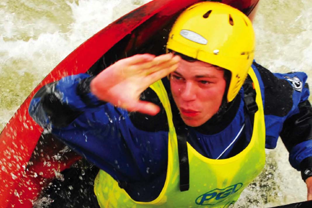 young man in racing gear rides through rapids in a freestyle whitewater kayak