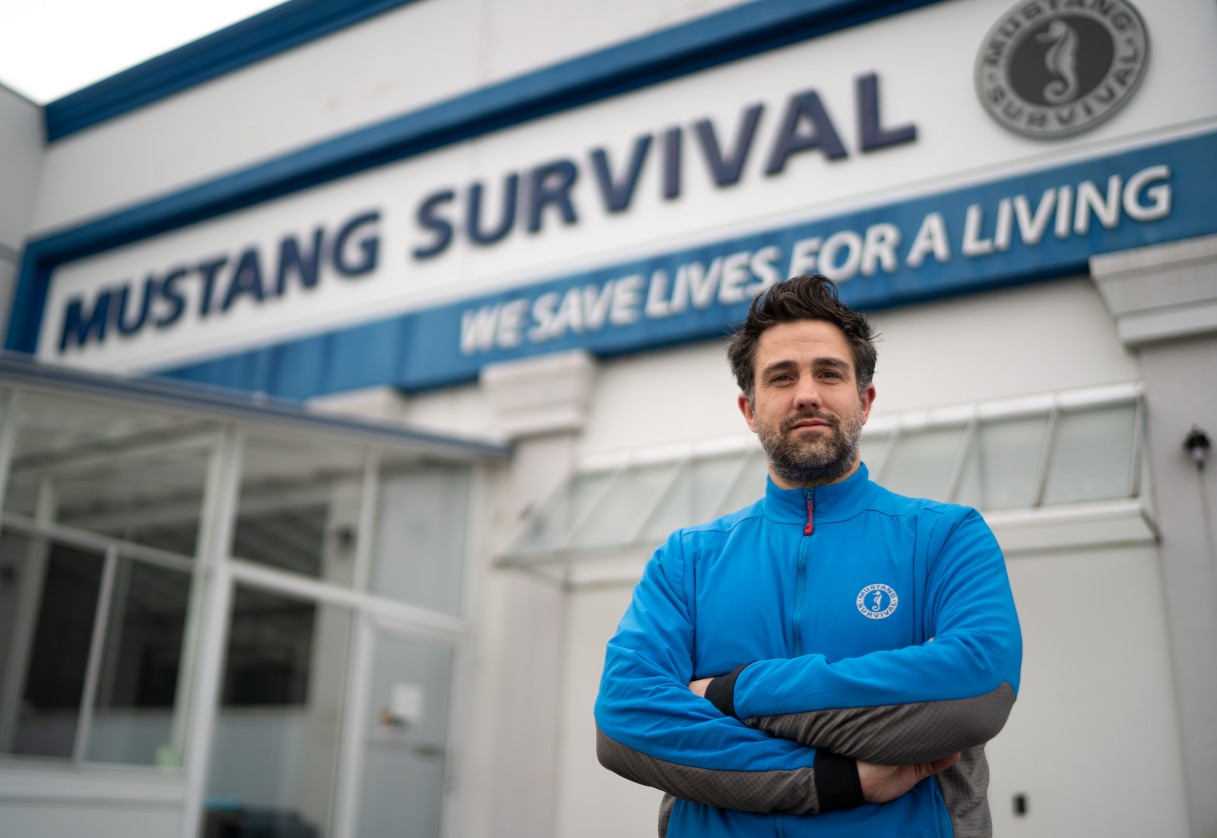 Man stands in front of Mustang Survival sign on building