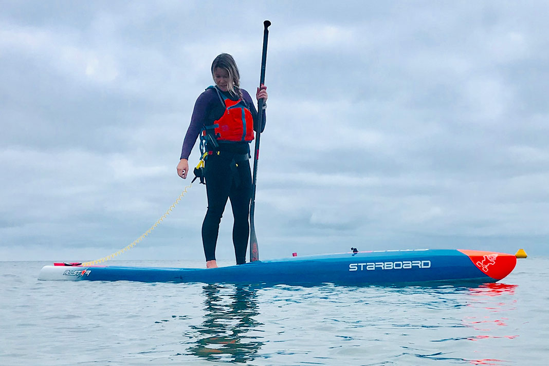 Samantha Rutt standing on her expedition paddleboard holding her paddle
