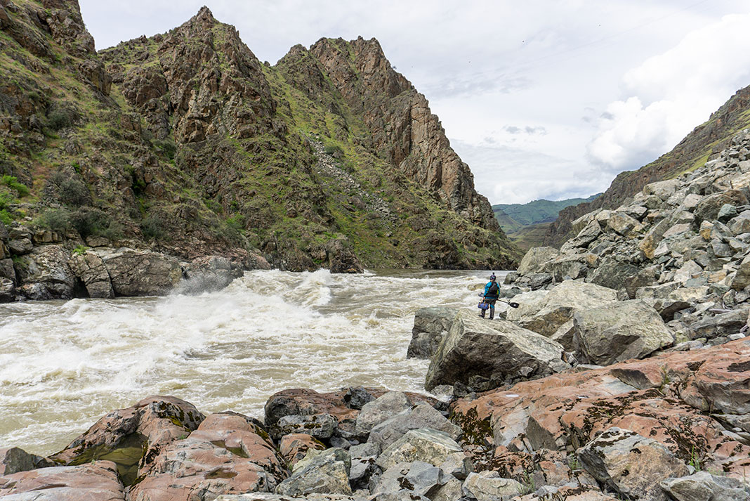 woman in whitewater paddling gear scouts a rapid on the Salmon River