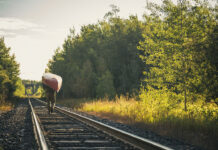 person portaging a canoe along train tracks in the sunlight