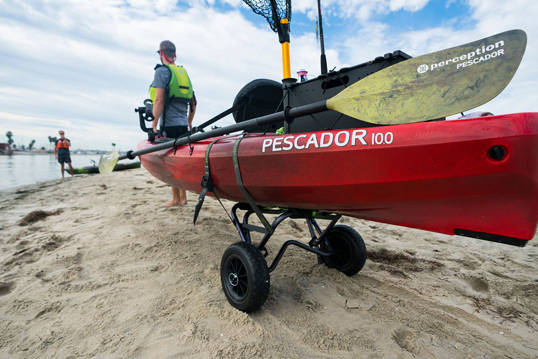 man hauls rigged Perception Pescador fishing kayak to the water