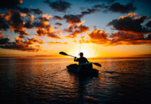 kayak angler on the water silhouetted by sunset