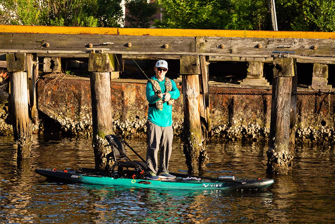man stands and fishes from the Vibe Cubera 120 Hybrid fishing kayak paddleboard hybrid