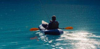 person fishes from an inflatable paddle kayak