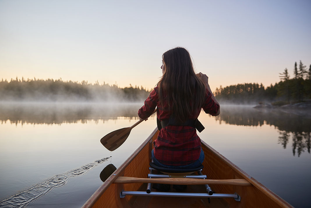woman paddles from the bow of a canoe