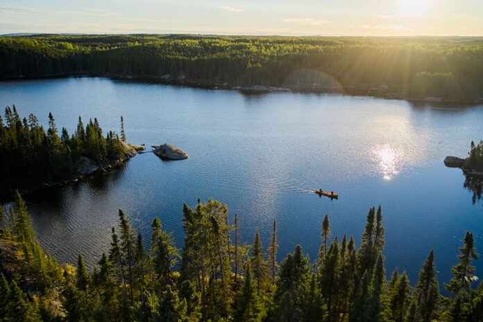 wide shot of two people paddling a canoe through Minnesota's Boundary Waters Canoe Area