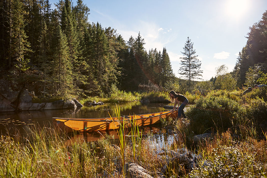 woman handles ultralight canoe on sunny day in Minnesota's Boundary Waters Canoe Area