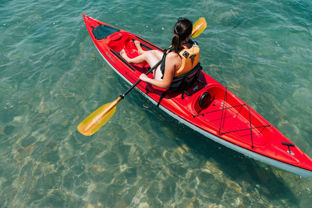 woman paddles a solo touring kayak