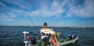 kayak angler shows off his fishing skills by holding up a big jack caught from a Sea Eagle boat