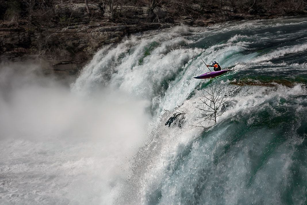 Whitewater kayaker goes over waterfall.