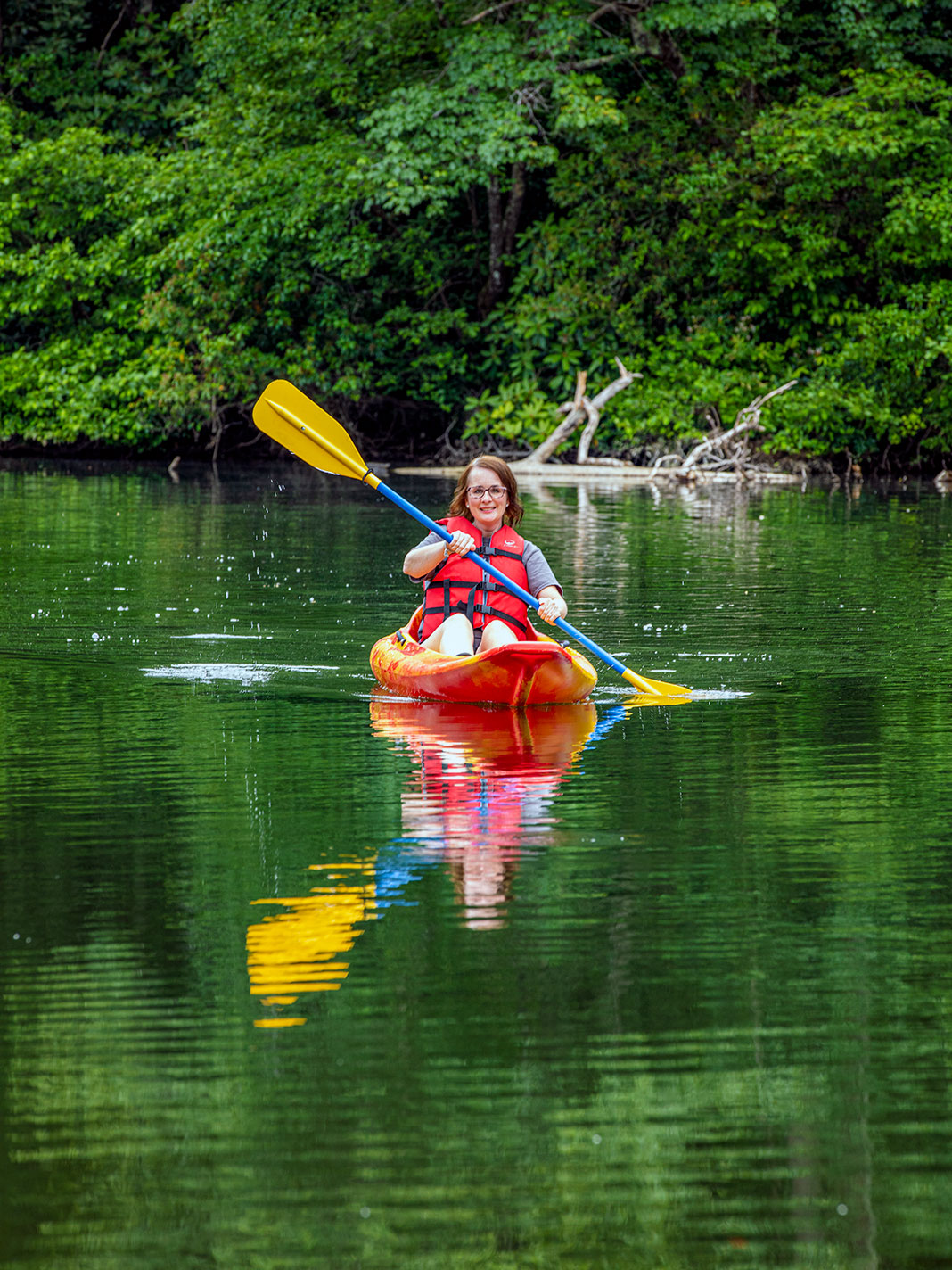 a woman kayaking in front of green trees