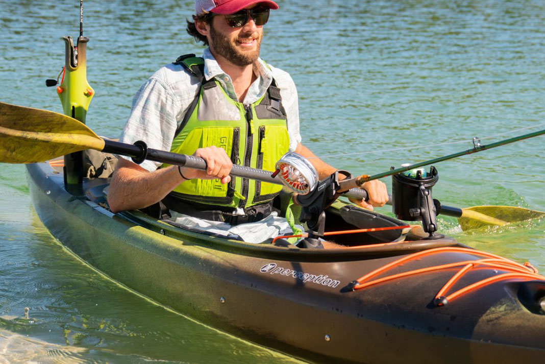 Man paddles in a sit-in fishing kayak