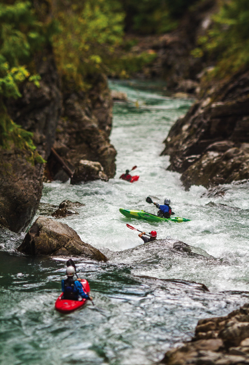 a group of people kayak down river rapids surrounded by rocks