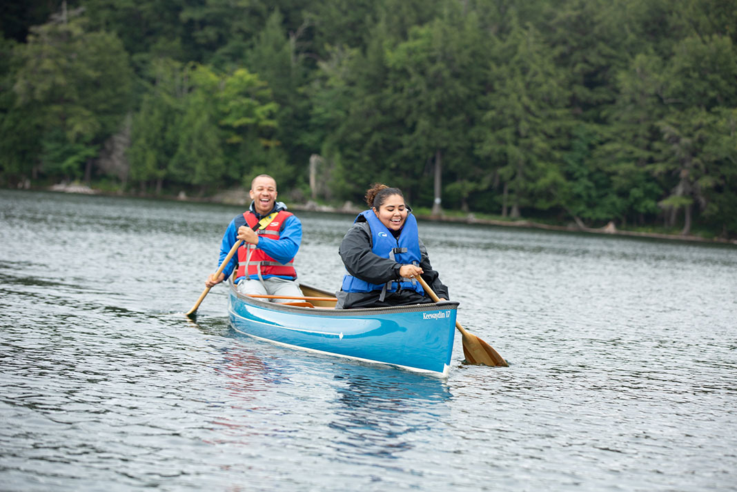 Man and woman paddling a blue canoe.