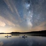 Starry Night: The Cosmic Story Behind A Beautiful Kayaking Photo a photo of two kayakers floating on still water under the starry night sky