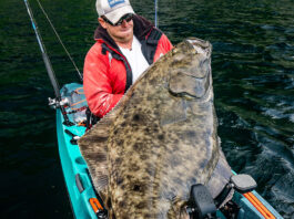 big game angler Adam Fisk holds up a huge halibut caught from a kayak in Alaska