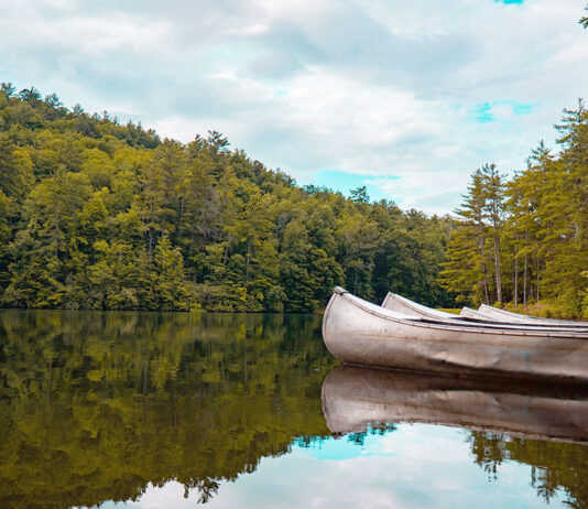aluminum canoes sit on a calm lake