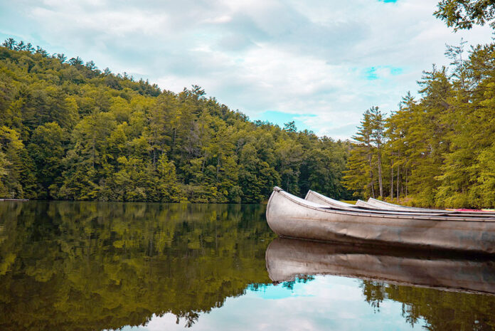 aluminum canoes sit on a calm lake