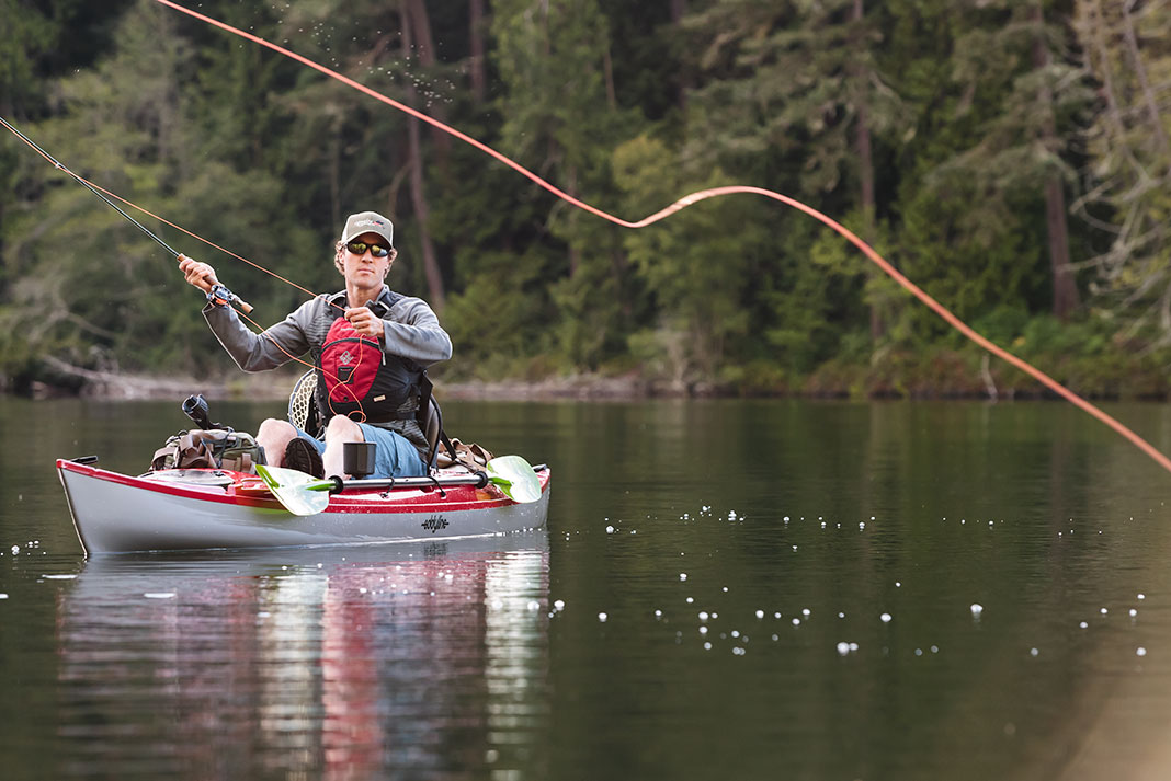 man casts fly line from a fishing kayak