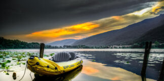 Intex inflatable kayak sits on glassy water in front of a mountain under dramatic clouds