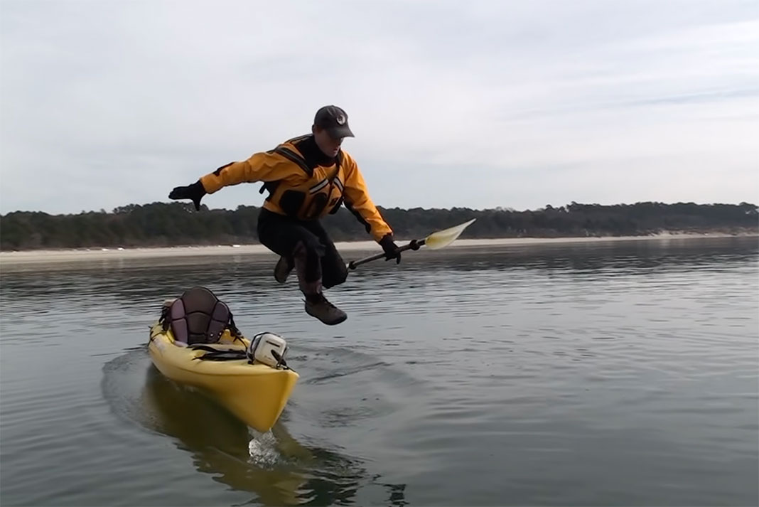 man tests a drysuit by jumping from a fishing kayak