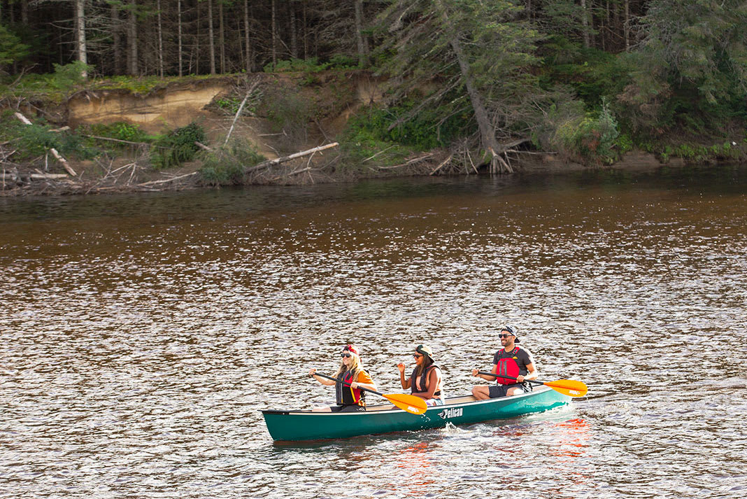 three people paddle in a Pelican canoe