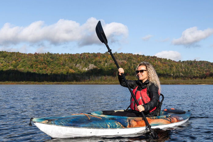 woman paddles a sit-inside Pelican kayak