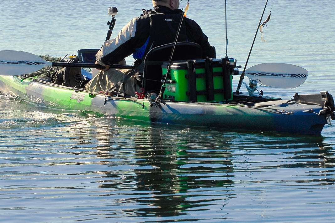 Person padding a green and black sit-on-top fishing kayak with rods