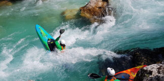 two people in whitewater kayaks perform moves in rapids