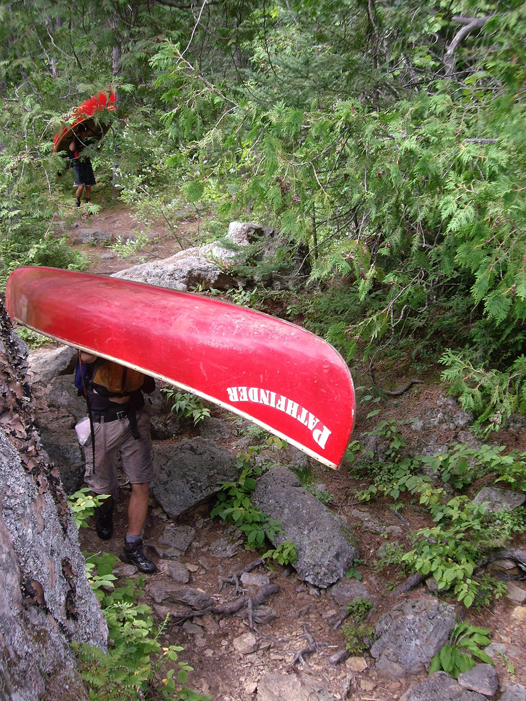 two people portage red canoes through the wilderness near Petawawa, Ontario