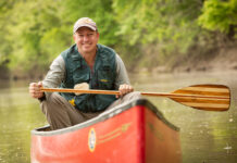 Neal Moore poses in his canoe, paddle in hand, after completing his canoe trip across America