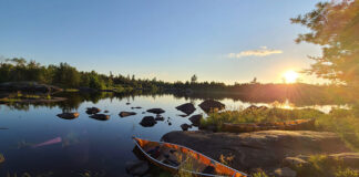 A canoe rests a the edge of a rocky lake in the Boundary Waters at sunrise