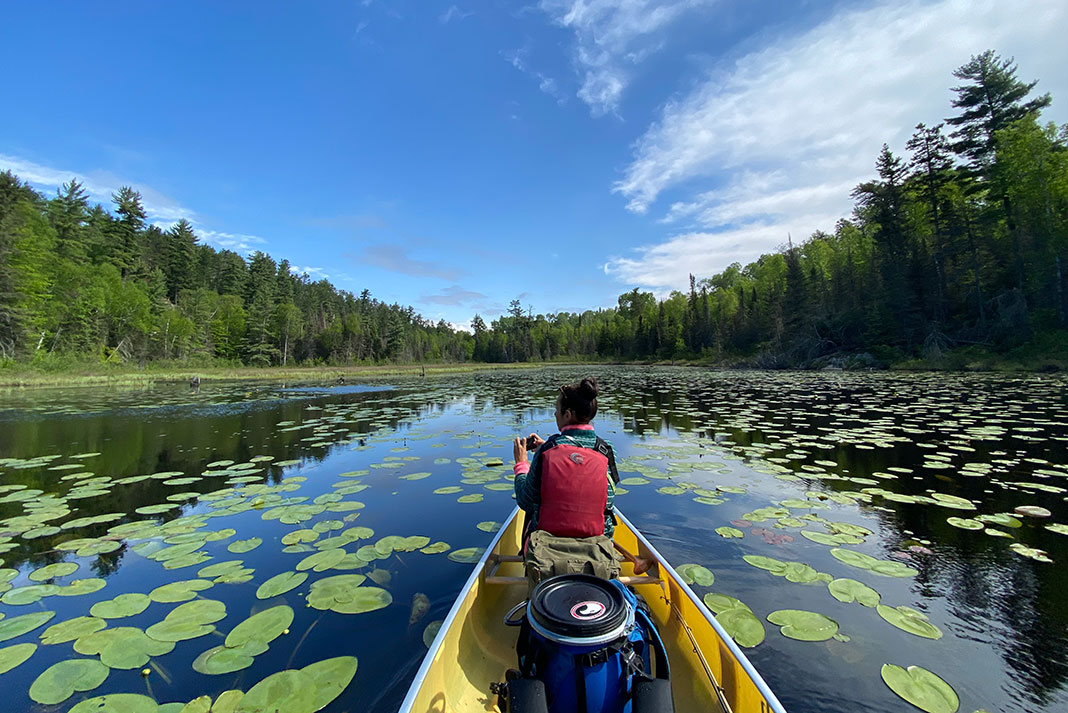 woman takes photos from bow of a canoe in Boundary Waters