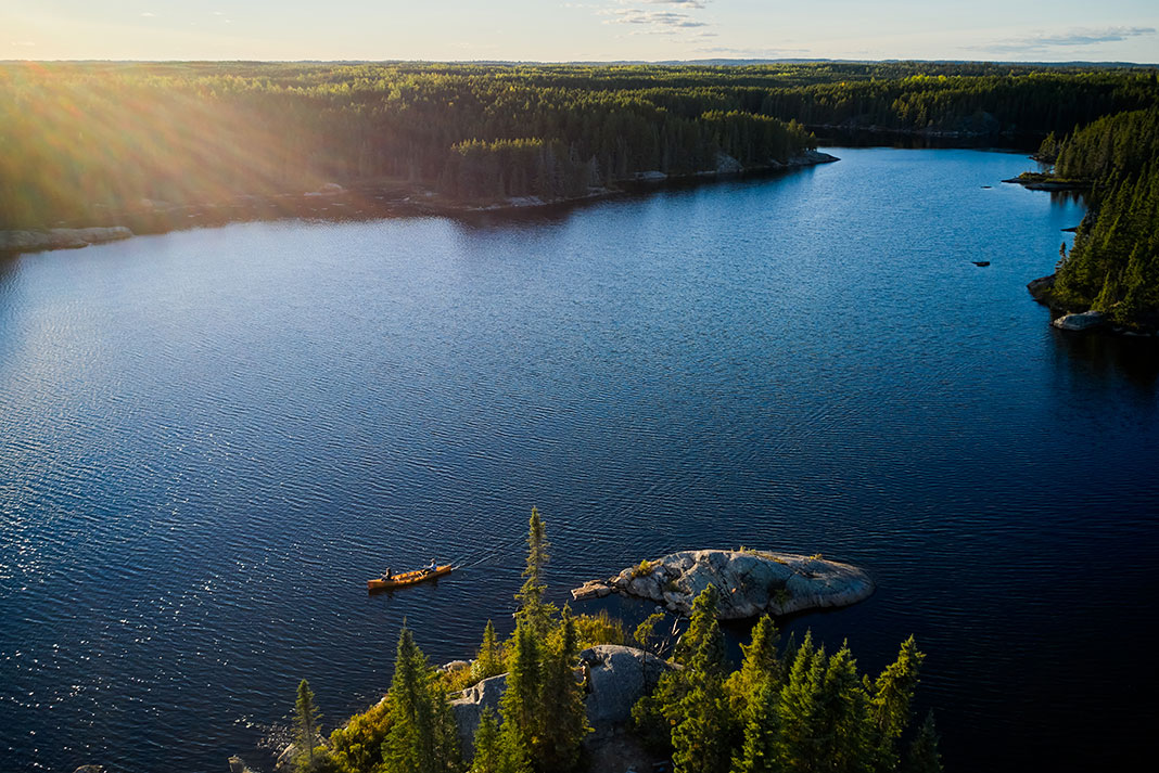 wide shot of two people paddling a canoe through Minnesota's Boundary Waters Canoe Area
