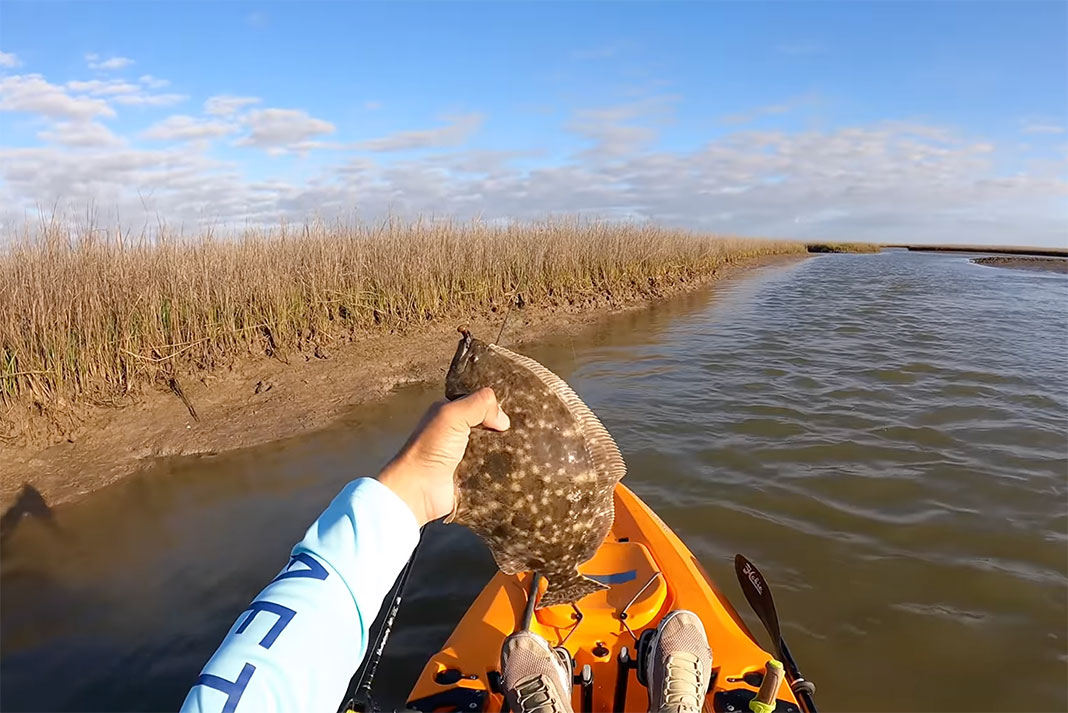 angler holds up a flounder caught while fishing skinny water in Texas coastal marshes