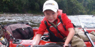 kid holds up his catch while kayak fishing