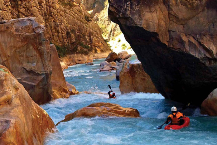 two whitewater kayakers paddle down a rocky gorge in Nepal's Himalaya Mountains