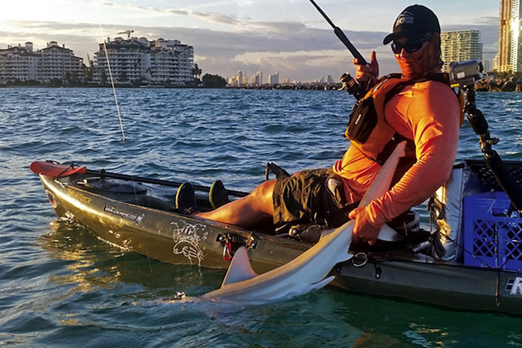 kayak angler grabs a shark he caught by the tail