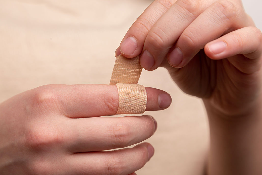 person wraps a finger in a bandage to demonstrate how to treat a blister