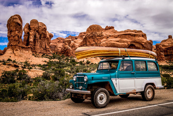 a jeep with a wooden canoe tied to the roof
