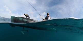 an angler catches a fish from a kayak equipped with a trolling motor