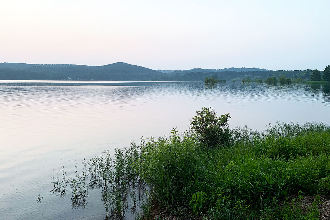 View of a lake with tree-covered hills in the background.