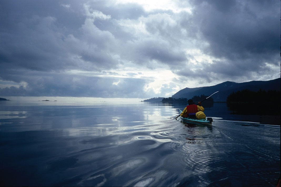 a person goes long haul kayaking in dark, cloudy weather