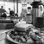 black and white photo of a lunch plate in a diner with a stack of paddling books and other people dining in the background