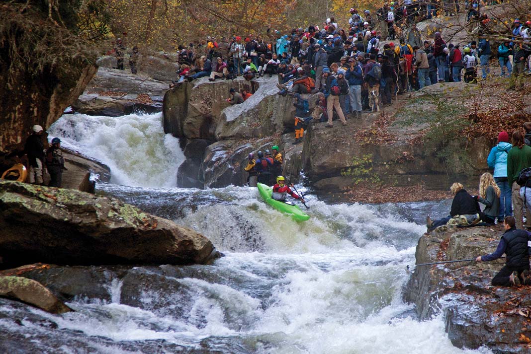 a paddler participates in the Green River Narrows Race while crowds watch from surrounding rocks
