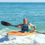 Recreational Kayak Review: Pelican Trailblazer 100 NXT man paddles Pelican Trailblazer NXT kayak in light surf