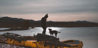 woman and dog silhouetted in front of a pair of yellow packrafts
