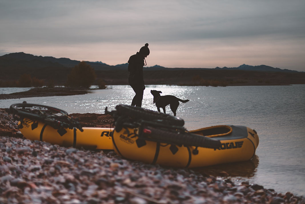 woman and dog silhouetted in front of a pair of yellow packrafts