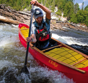 man paddles an open canoe
